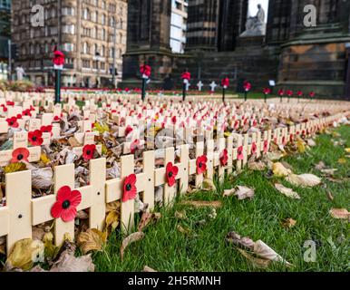 Edinburgh, Scotland, United Kingdom, 11th November 2021. Garden of Remembrance: close up of poppy crosses amongst Autumn leaves in front of the Scott monument just before the service at 11.00am in Princes Street Garden Stock Photo