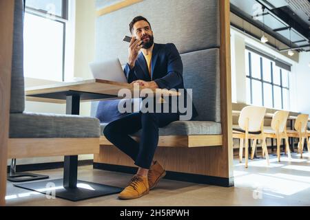 business professional speaking on a phone call. Focused young businessman communicating with his business partners over the phone. Young entrepreneur Stock Photo