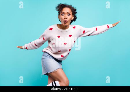 Photo of sweet impressed afro girl wear heart print pullover arms sides showing plane isolated blue color background Stock Photo