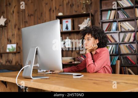 young african american woman using computer mouse while looking at monitor at home Stock Photo