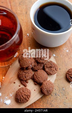 Vertical shot of dry chocolate cupcakes and a cup of coffee on a wooden table Stock Photo