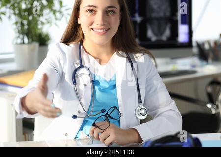 Woman doctor giving hand for handshake in clinic Stock Photo