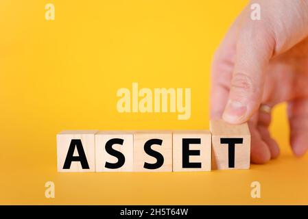 The word assets written on wooden cubes with assets icon on yellow background. Asset management or financial accounting concept. Stock Photo