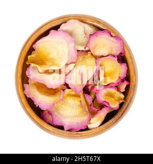 Dried whole rose petals in a wooden bowl. Petals of a light pink colored garden rose, called China, Chinese or Bengal rose. Rosa chinensis. Stock Photo