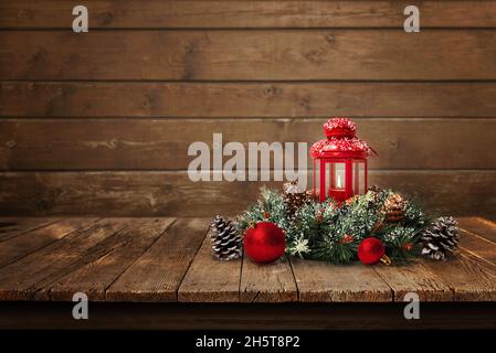 Christmas composition on old wooden table with copy space beside. Christmas tree branch with red lantern, balls and pine cones Stock Photo