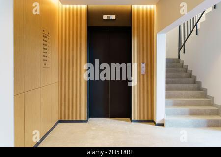 Elevator in the lobby hall of an apartment building. Modern decor and wood finishing of the ground floor and entrance. High quality photo Stock Photo