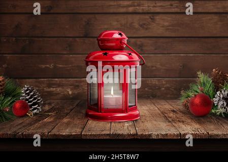 Red lantern with a flame on an old wooden table. Christmas scene with decorations. The concept of home warmth during the Christmas holidays Stock Photo