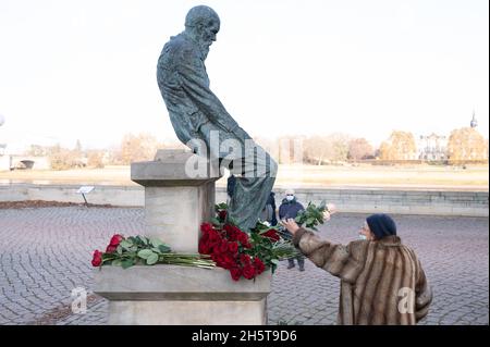 Dresden, Germany. 11th Nov, 2021. A woman lays flowers at the monument during a press event to honor Fyodor Mikhailovich Dostoyevsky. The occasion is the 200th birthday of the Russian writer. Credit: Sebastian Kahnert/dpa-Zentralbild/dpa/Alamy Live News Stock Photo