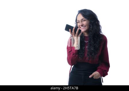 Pretty Latin Hispanic woman with long thick hair wearing glasses on white background indoors making expressions and gestures, happy, smiling, talking Stock Photo