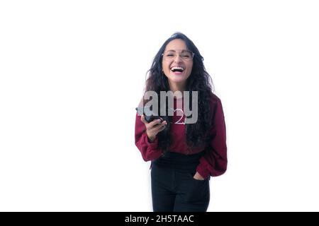 Pretty Latin Hispanic woman with long thick hair wearing glasses on white background indoors making expressions and gestures, happy, smiling, talking Stock Photo