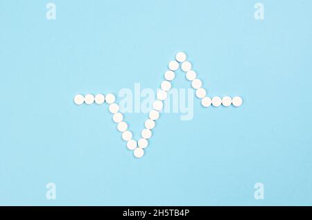 Pills in the form of a cardiogram on a blue background Stock Photo