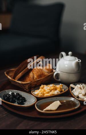 Traditional Turkish breakfast with fried egg, black olives, croissant, bread, cheese, butter in honey and tea on a wooden table. Organic, fresh and ta Stock Photo