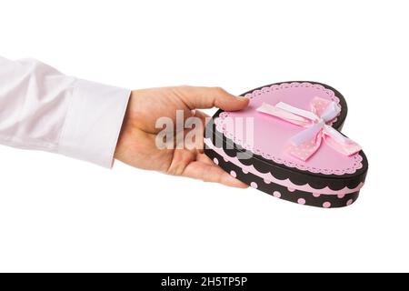 Man holds in his hand a gift box in the shape of a heart, isolated on a white background, template for designers Stock Photo