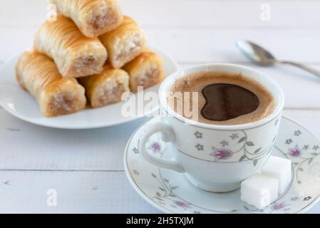A cup of frothy coffee and a plate of baklava for breakfast in Turkish style. Stock Photo