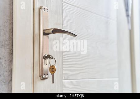 A key with a key fob in the keyhole of the door. Buy a new home concept. Real estate market. Stock Photo
