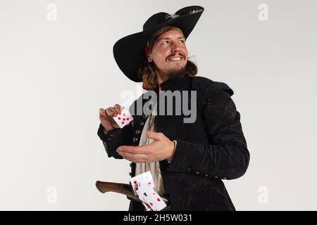 Cropped portrait of man, medeival pirate with pistol playing cards isolated over white background Stock Photo