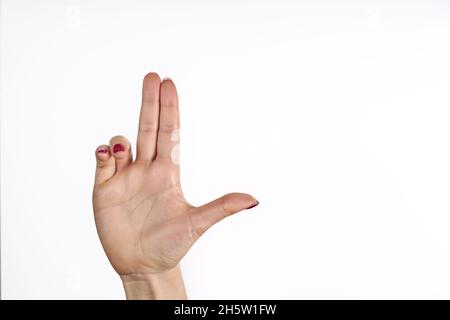 Woman's hand making shooting gun, gesture. hand pistol gesture on isolated white background. Woman hand pointing with two fingers. Stock Photo