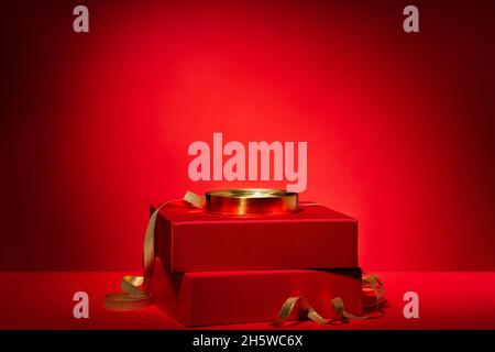 Empty red podium made of gift boxes and golden circle and decor on a red background. Pedestal, showcase for products and cosmetics. Chinese New Year c Stock Photo