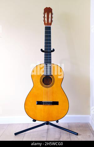 An acoustic classic six string nylon strung Spanish or classical guitar. The guitar is shown on its own resting in a guitar stand Stock Photo