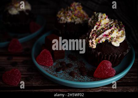 Tasty dark chocolate cupcake with colourful sprinkles white cream topin, truffles and heart shaped candy for christmas celebration for loved ones Stock Photo