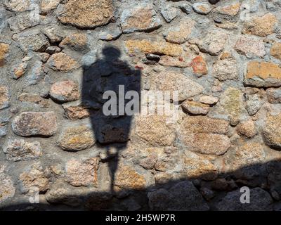 Shadow of a street lamp on a stone wall of the castle of Trujillo. Stock Photo