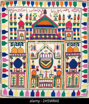Detail of Hazara prayer stone cloth Afghanistan. Embroidered cloths with minaret; mosque; Arabic characters; prayer niche motifs. Prayer stone cloths are used to hold the prayer stone (mohr or turba) used by Shiite muslims. The prayer stones are made of baked clay from Karbala. The prayer stones are kept wrapped in the cloths in the house or on the body. When praying one puts the prayer stone cloth on the prayer rug. Prayer cloths and stones are placed on the prayer rug in such a way that one touches the stone with one's forehead when bending over during prayer. Stock Photo