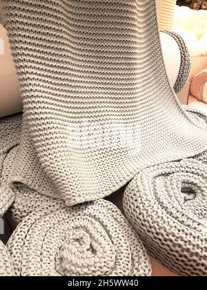 Natural knitted woolen cotton fabric rolled coverlid background. Stock Photo