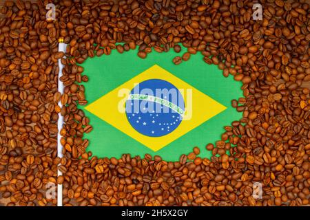 Roasted coffee beans and Brazilian flag on the table. Brazilian Coffee price rise concept. Arabica Coffee Futures Climb from Brazil. Top view. Close-u Stock Photo