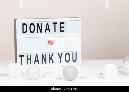 Christmas donation, charity. White lightbox with message Donate and Thank you standing on the table. Front view, close up Stock Photo
