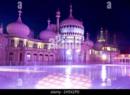 The Royal Pavilion, Brighton, lit up with coloured LED uplighters behind the winter ice skating rink erected in the Pavilion gardens. Brighton, East Sussex, England, UK Stock Photo