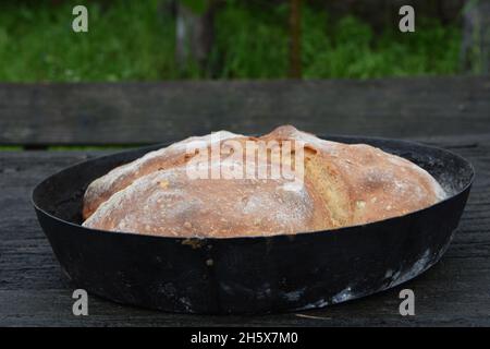 Selective focus shot of freshly backed bread in a pan on a wooden surface Stock Photo