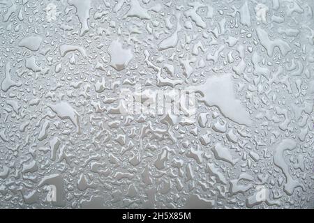 Irregular patterned water drops on a silver-coloured shiny metal surface Stock Photo