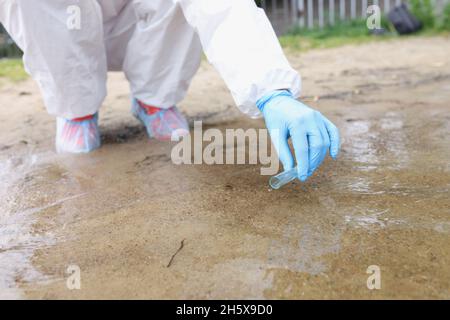 Environmentalist in protective suit and gloves taking water samples from lake closeup Stock Photo