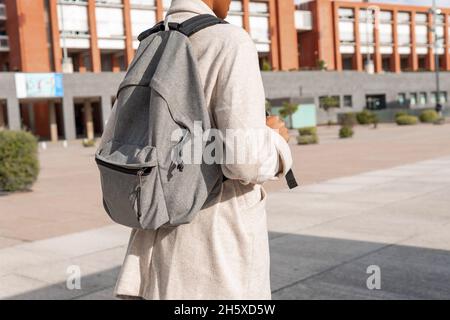 Back view of Anonymous African American female student with backpack standing on walkway near modern university building on street Stock Photo