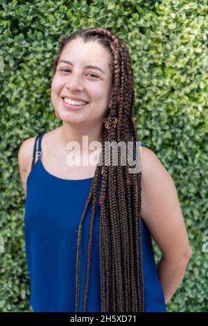 Charming young lady with piercing and fist near mouth looking at camera in redness on blue background Stock Photo