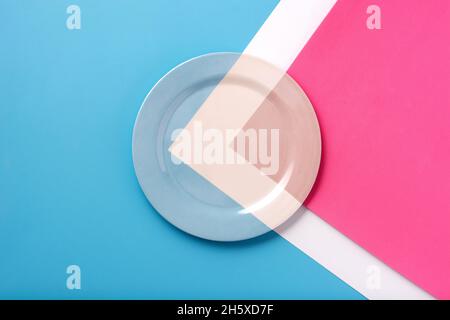 Top view of a plate with white line and with blue and pink colors on a table of the same color Stock Photo