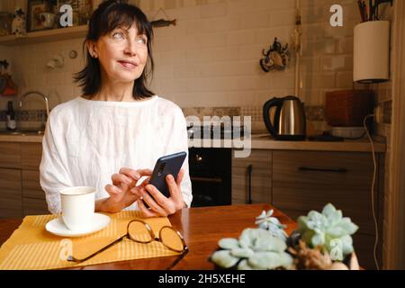 Ground level of mature female with closed eyes and raised arms practicing yoga on mat in room Stock Photo