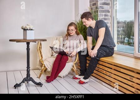 Online shopping using laptop, young couple is choosing furniture in new apartment. Stock Photo