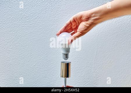 Replacing an LED light bulb in household lighting fixture for home. Stock Photo