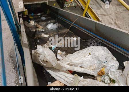 Moscow. Russia. Autumn 2020. Garbage on the tape rises up. Garbage sorting plant, dirty tape in the remains of garbage. Stock Photo