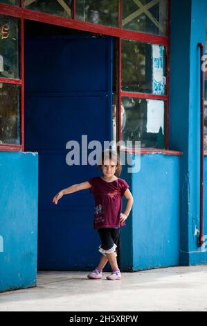 Young little girl dances and plays by herself in a doorway of a shop in Havana, Cuba Stock Photo