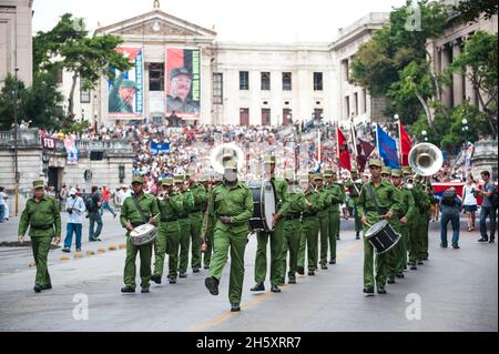 Cuban Drum Major leads band playing at an event in front of photos of  Fidel Castro and Raul Castro at the University of Havana, in Havana, Cuba. Stock Photo