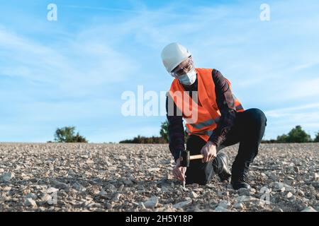 Engineer man doing topographic measures on land for construction work during coronavirus outbreak - Focus on face Stock Photo