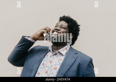 Shallow focus of a smiling black man talking on the phone outdoors Stock Photo