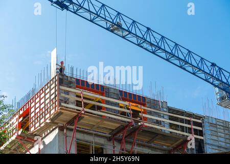 A construction worker stands on the rafters of the upper floor. The builder is installing supports for the concrete. Stock Photo