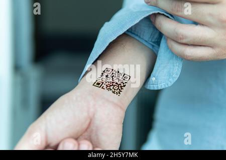 QR code on the person's wrist. The concept of chipping a person to control or simplify the work with personal data, close-up. Stock Photo