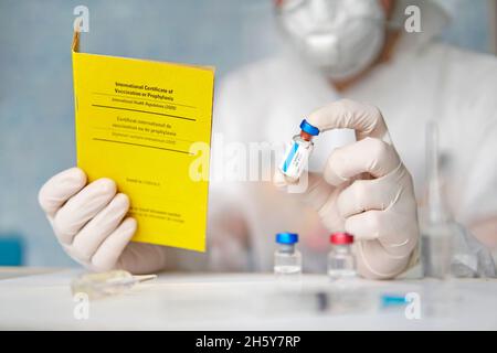 international certificate of the vaccination before travel. The laboratory assistant in the laboratory makes notes about vaccinations in the yellow do Stock Photo