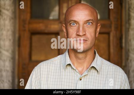 Bald man, dressed in casual shirt on, was amazed and surprised, looking at the camera with blue eyes. Emotional intent facial expression Stock Photo