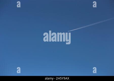 White contrail from an airplane in a clear blue sky. Copy space. Flight in good weather Stock Photo