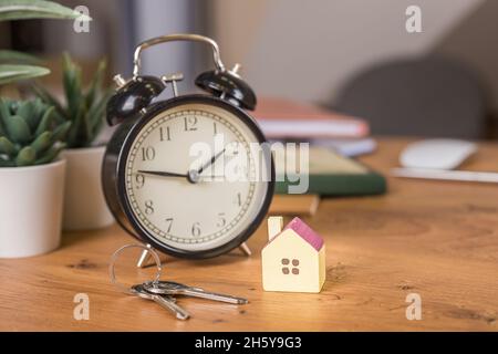 Model house on construction plan for house building, keys, red alarm clock and calculator. Real Estate Concept. Stock Photo